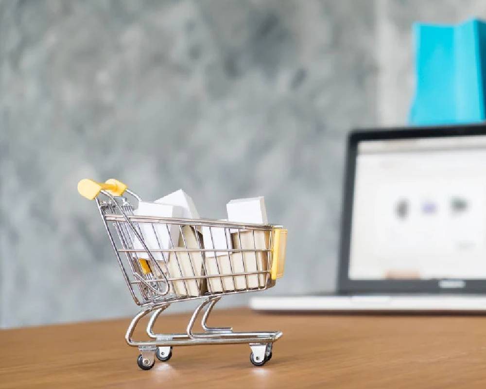 A small shopping cart in front of a laptop